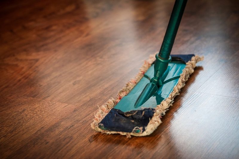 A flat mop being pushed across a dark hardwood floor
